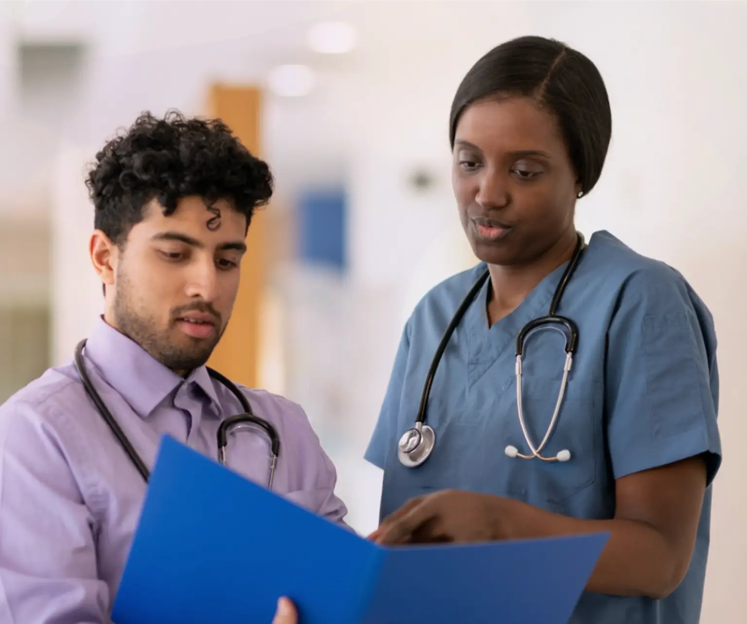 Two healthcare professionals looking at information in a medical chart. Actor portrayal.