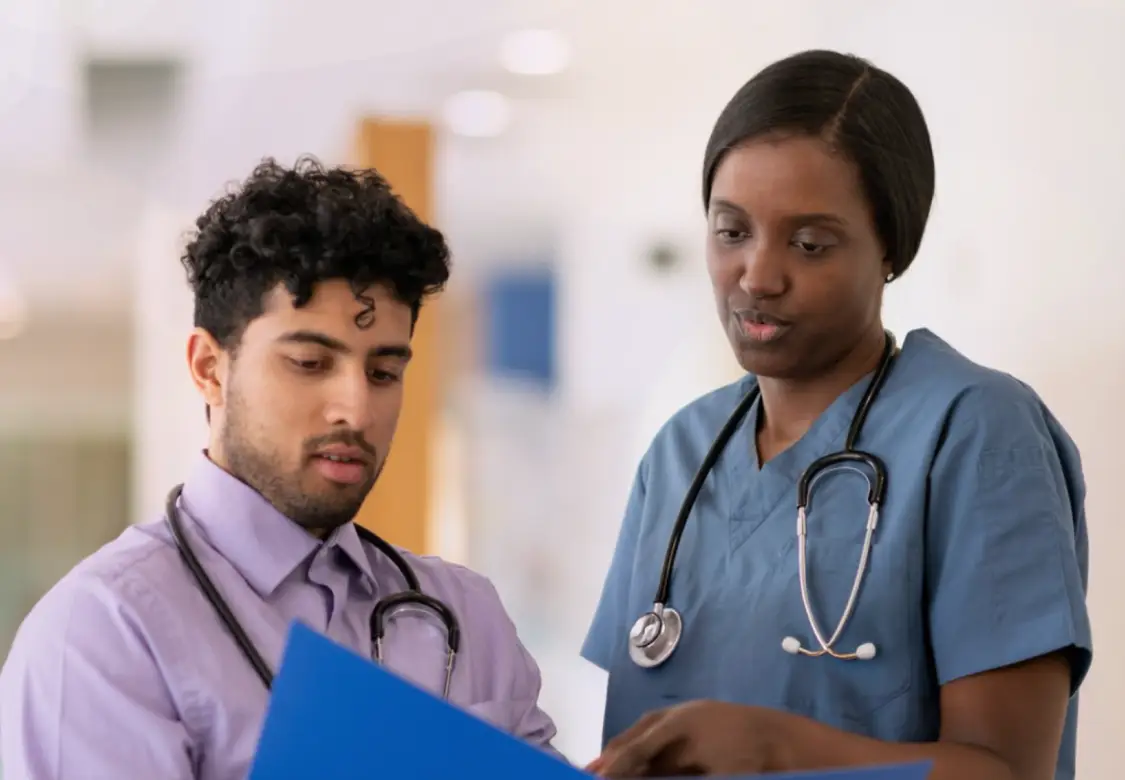 Two healthcare professionals looking at information in a medical chart. Actor portrayal.
