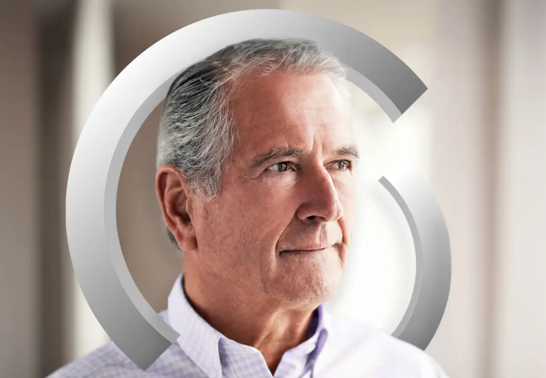 A man with gray hair, wearing a light-colored formal shirt, looking off to the distance. Actor portrayal