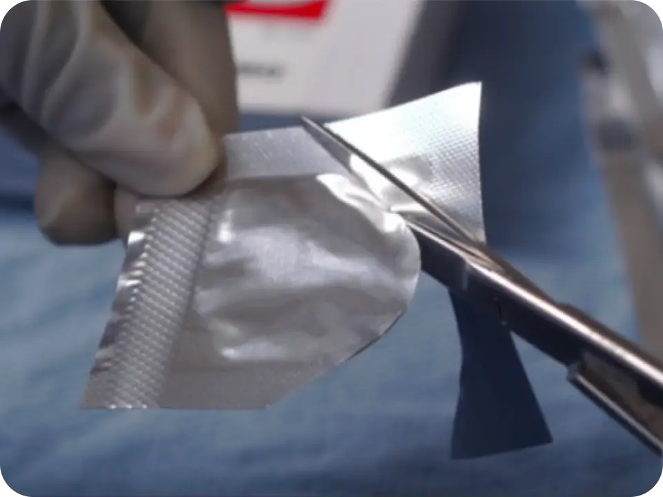 Hand holding a pouch, while the pouch is being cut open.