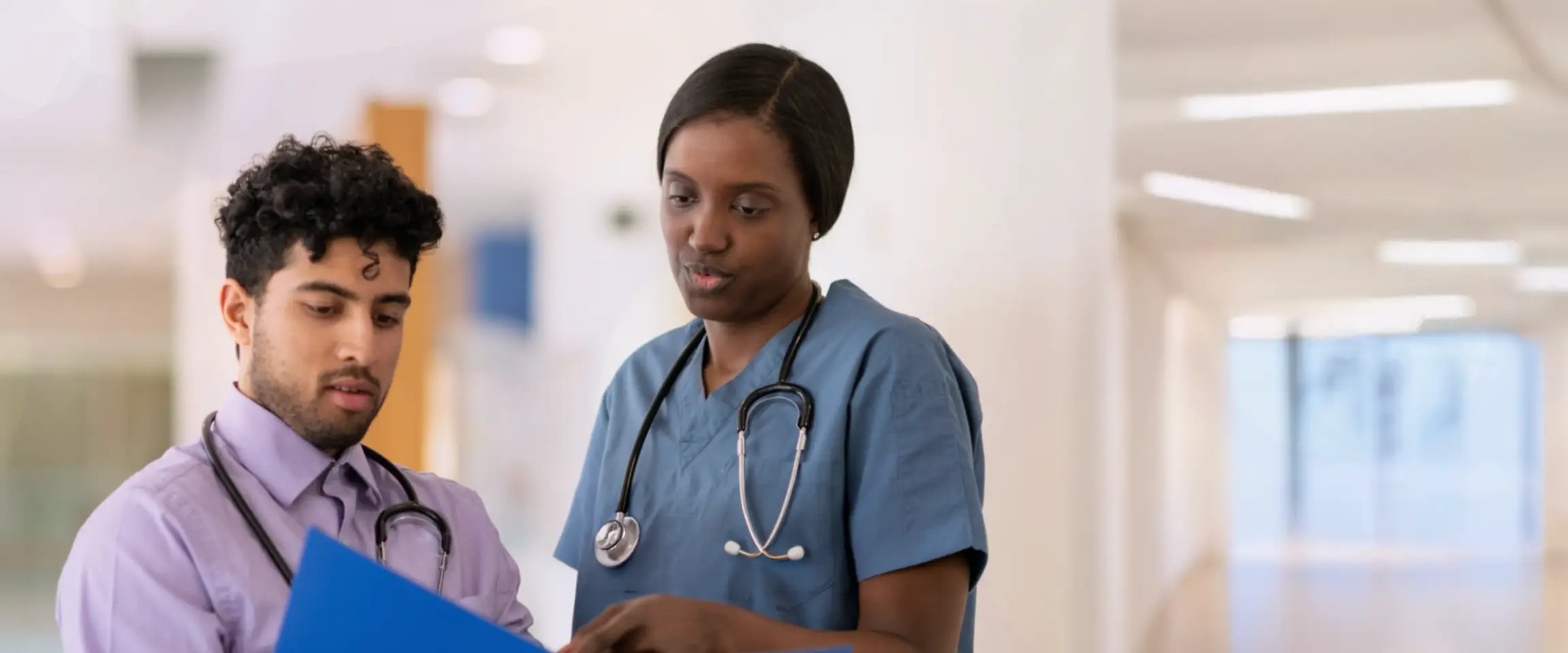Two healthcare professionals looking at information in a medical chart. Actor portrayal.